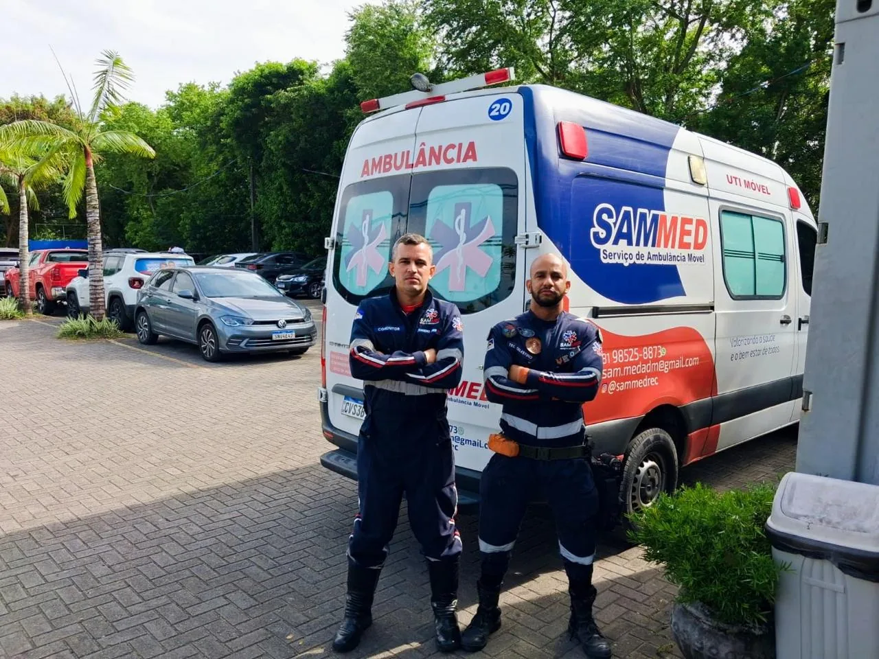 Dois profissionais uniformizados da SAMMED em frente a uma ambulância UTI móvel