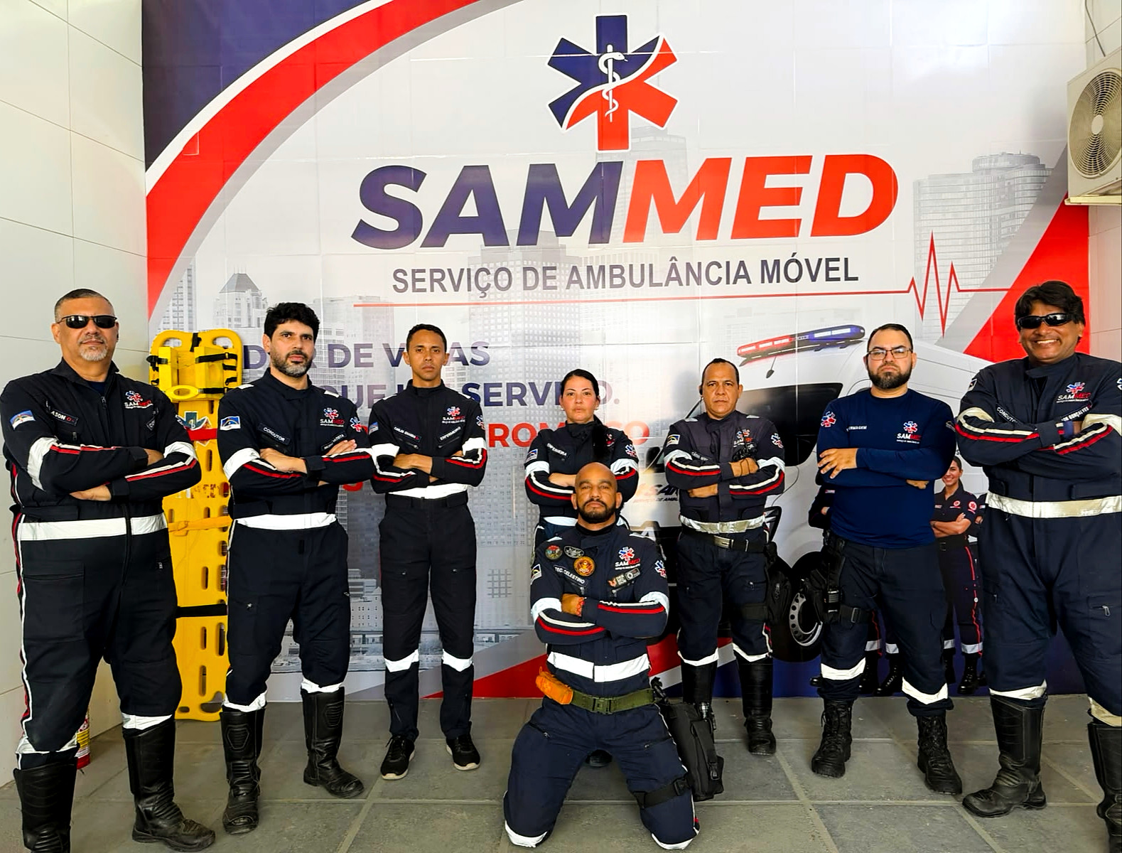 Equipe da SAMMED reunida diante do painel institucional